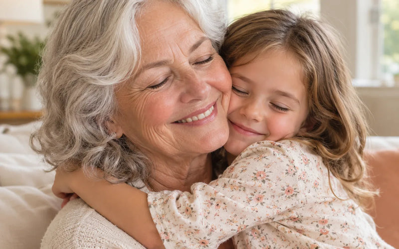 A grandmother hugging her granddaughter close on the sofa