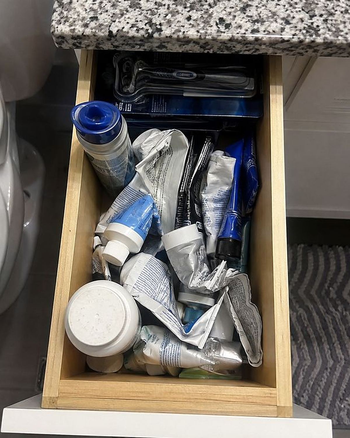 An open bathroom drawer full of creams, sprays and powders