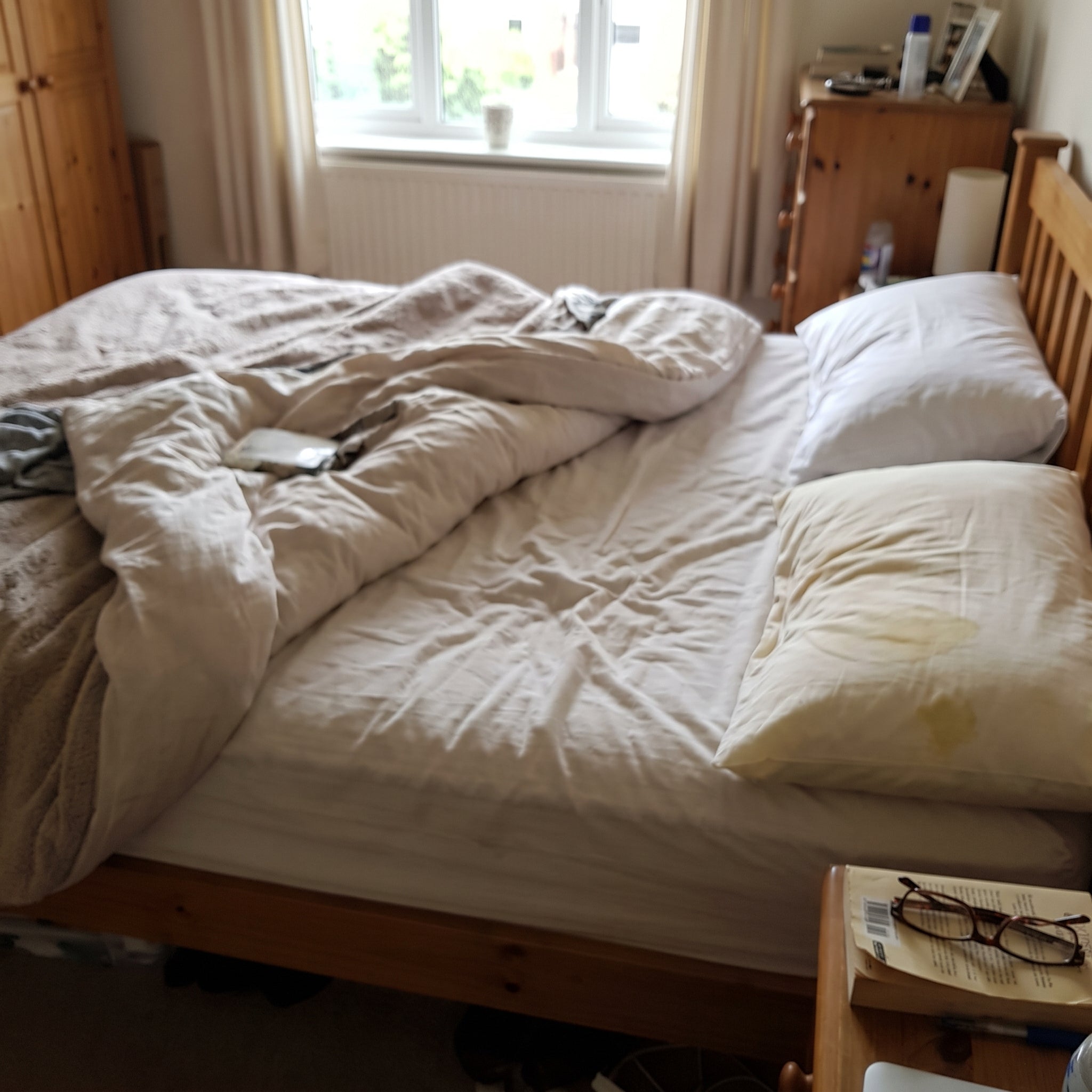 A bedroom with a yellowed pillowcase on one side of the bed
