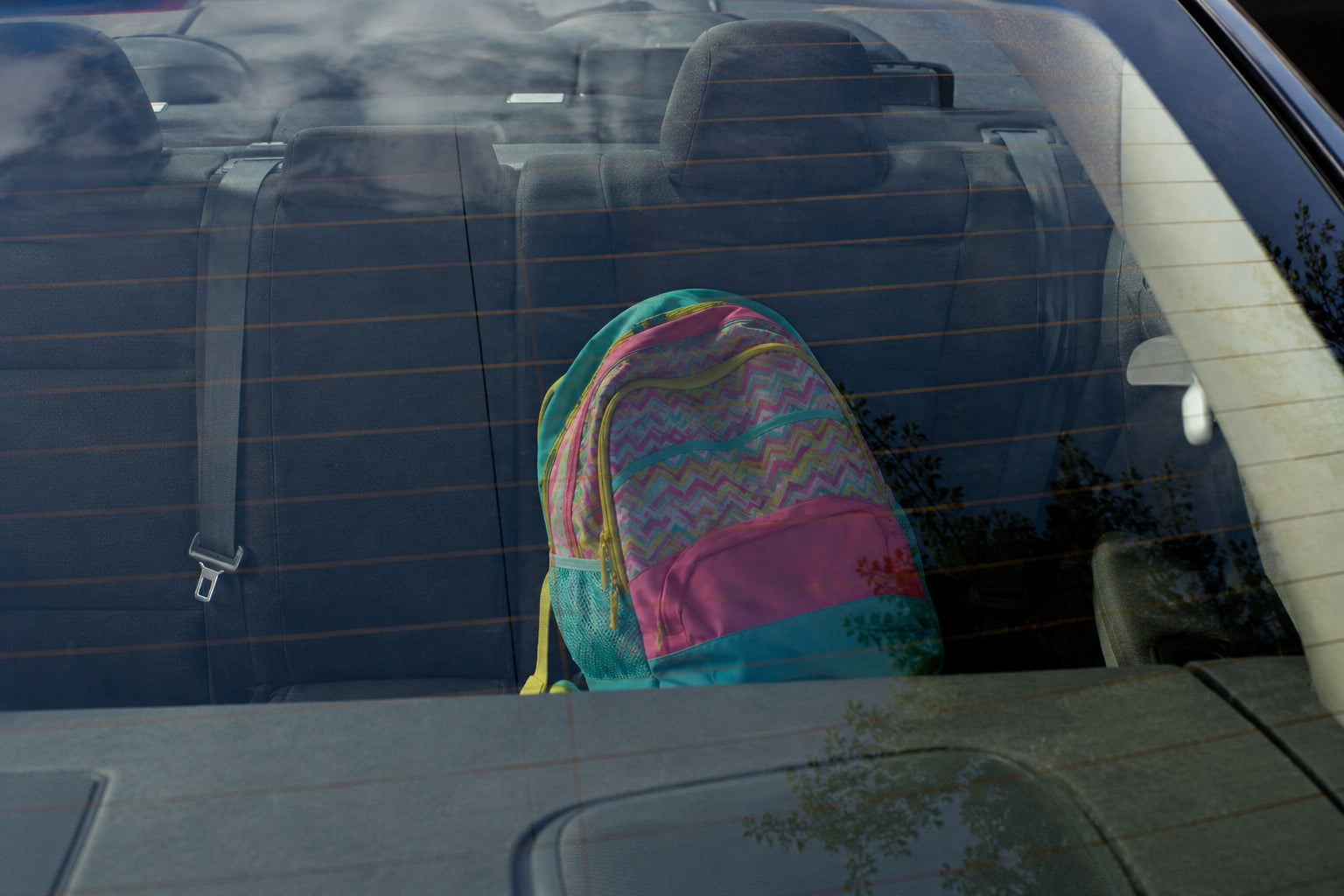 A child's school bag on the back seat of a car