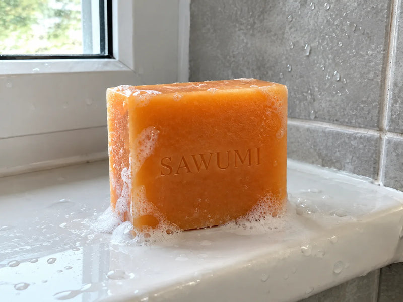 A SAWUMI persimmon soap bar on a bathroom windowsill